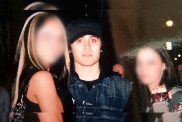 Jared Leto indossa cappello e giacca jeans tra due figure femminili sfocate. Jared Leto accusato da quattro donne di violenza sessuale