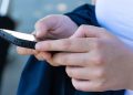 Ragazzo con in mano un telefono. Recensioni online l'Antitrust chiede lo scontrino per verificarne l'autenticità