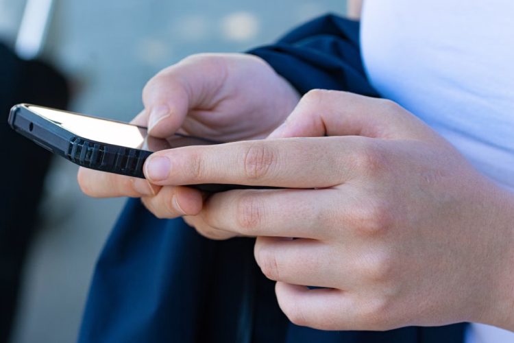 Ragazzo con in mano un telefono. Recensioni online l'Antitrust chiede lo scontrino per verificarne l'autenticità