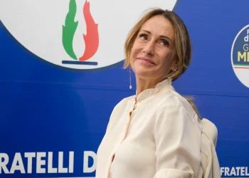Arianna Meloni sorride davanti al logo del partito Fratelli d'Italia