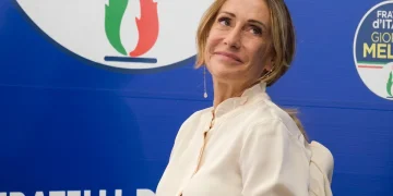 Arianna Meloni sorride davanti al logo del partito Fratelli d'Italia