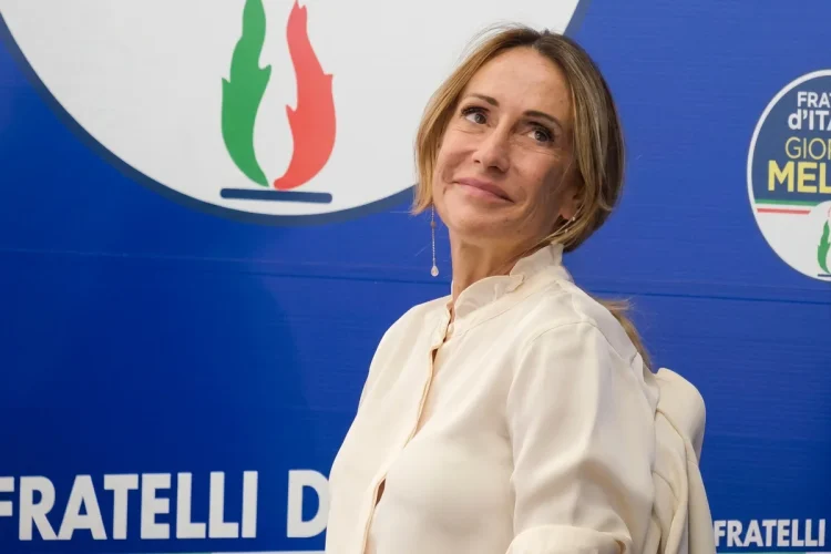 Arianna Meloni sorride davanti al logo del partito Fratelli d'Italia