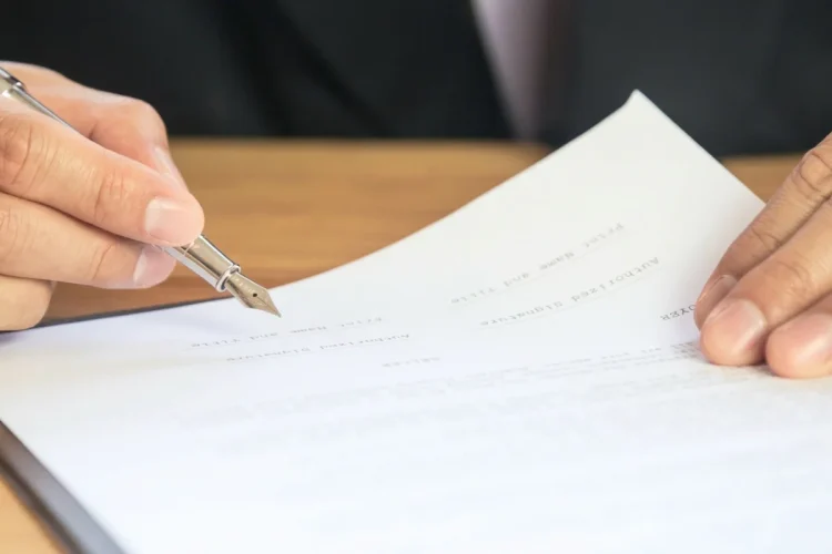 Mano di persona che firma documenti con penna stilografica