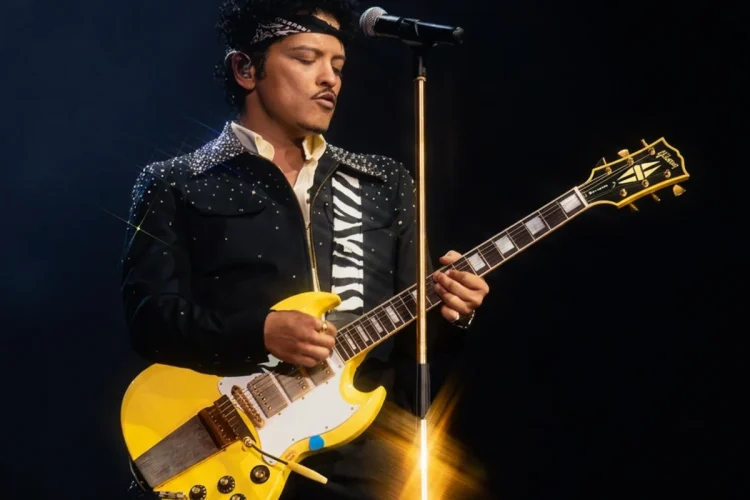 Bruno Mars suona la chitarra elettrica gialla durante un concerto dal vivo.