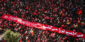 Folla manifestante con bandiere iraniane e striscione anti-Trump