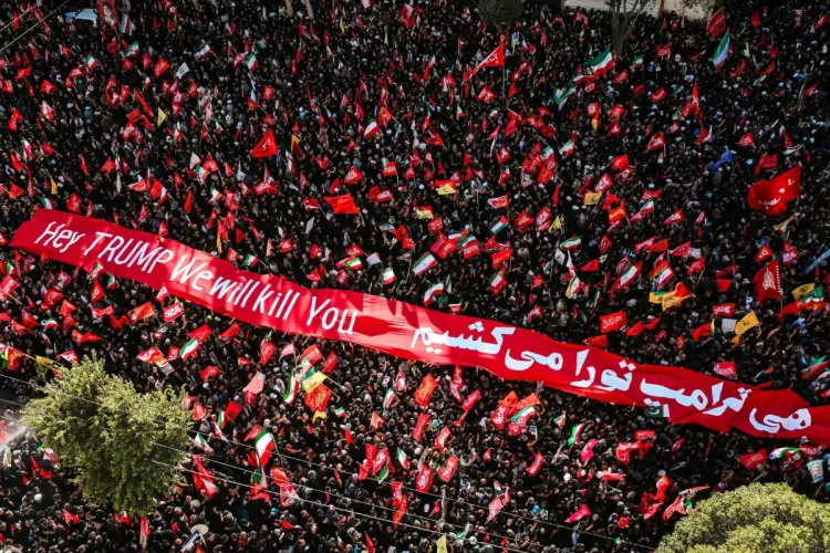 Folla manifestante con bandiere iraniane e striscione anti-Trump