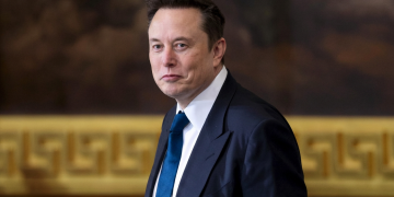 Elon Musk in completo scuro e cravatta blu guarda l'obiettivo. Musk attacca giudice e pm sul caso Roggero: "Sentenza folle, meritano la condanna"
