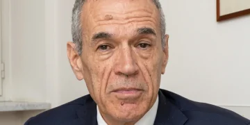 Carlo Cottarelli in primo piano con giacca blu e cravatta