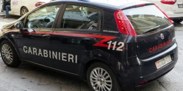 Auto dei Carabinieri parcheggiata, persone si muovono nello sfondo