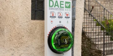 Defibrillatore pubblico DAE verde installato su muro esterno