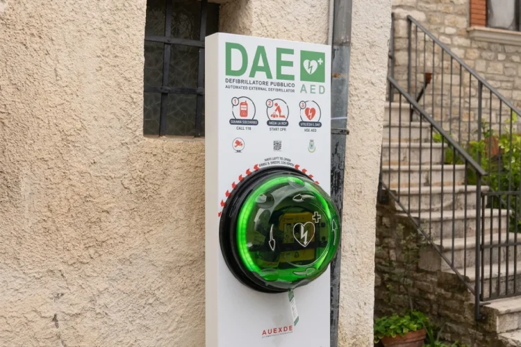 Defibrillatore pubblico DAE verde installato su muro esterno