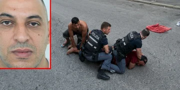 Fakir in primo piano e tre uomini con agenti di polizia a terra