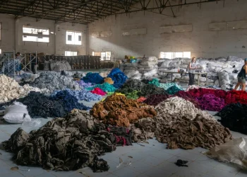 Donne lavorano in un magazzino tra cumuli di vestiti usati per riciclo