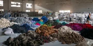 Donne lavorano in un magazzino tra cumuli di vestiti usati per riciclo