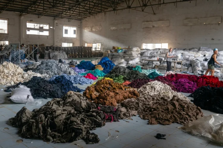 Donne lavorano in un magazzino tra cumuli di vestiti usati per riciclo