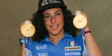 Sciatrice Federica Brignone sorride mostrando due medaglie olimpiche d'oro.