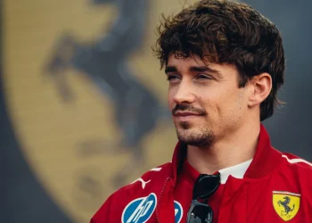 Charles Leclerc vestito Ferrari con giacca rossa, occhiali da sole appesi
