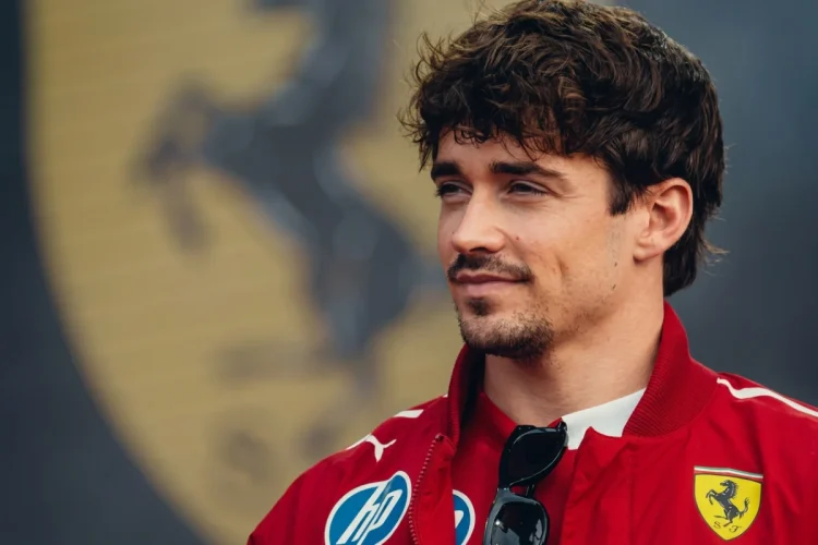Charles Leclerc vestito Ferrari con giacca rossa, occhiali da sole appesi