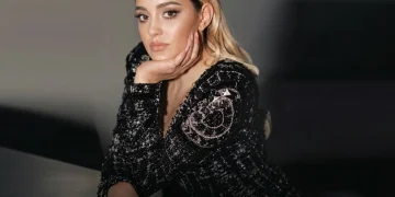 Donna bionda con giacca nera brillante in posa elegante