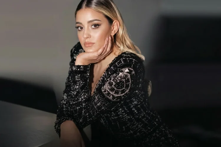 Donna bionda con giacca nera brillante in posa elegante