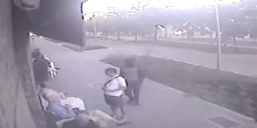 Persone sedute e in piedi su marciapiede, riprese telecamera di sorveglianza.
