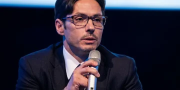 Pier Silvio Berlusconi con occhiali parla al microfono in evento pubblico