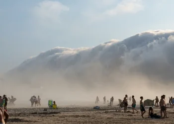 Fitta nebbia avvolge la spiaggia affollata di persone curiosi.