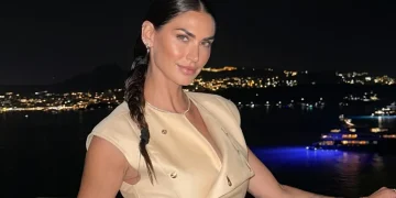 Melissa Satta sorride in abito beige su balcone notturno.