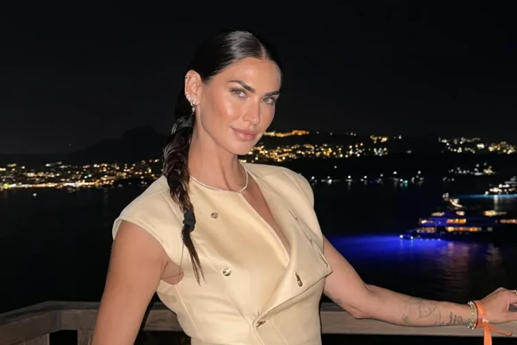Melissa Satta sorride in abito beige su balcone notturno.