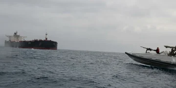 Nave militare con soldati insegue una grande petroliera in mare aperto.