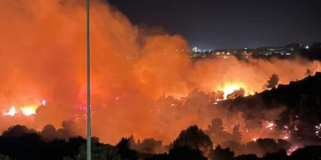 Vasto incendio boschivo illumina la notte, fiamme e fumo arancione