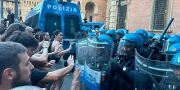 Manifestanti spingono contro agenti di polizia antisommossa con scudi
