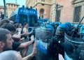 Manifestanti spingono contro agenti di polizia antisommossa con scudi