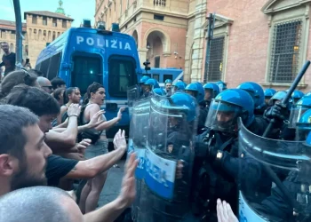 Manifestanti spingono contro agenti di polizia antisommossa con scudi