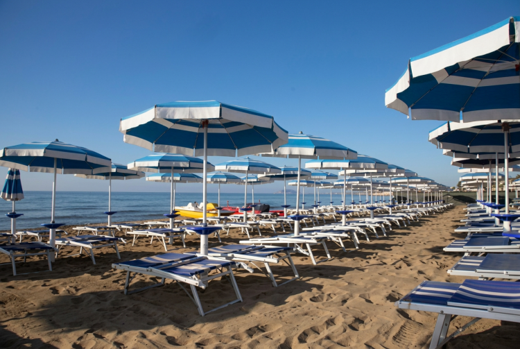 Ombrelloni e lettini allineati su una spiaggia di sabbia chiara. Ancona, tromba d'aria al Passetto: ombrelloni e lettini volano in aria