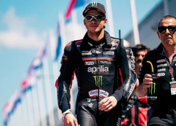 Marco Bezzecchi cammina in tuta da corsa Aprilia sulla pista