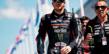 Marco Bezzecchi cammina in tuta da corsa Aprilia sulla pista