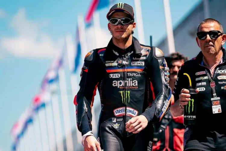 Marco Bezzecchi cammina in tuta da corsa Aprilia sulla pista