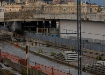 Cantiere ferroviario con traversine di cemento e barriere arancioni.