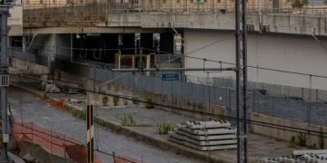Cantiere ferroviario con traversine di cemento e barriere arancioni.