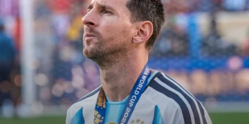 Lionel Messi pensieroso in campo con maglia Argentina, lanyard FIFA.