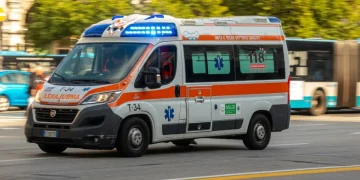 Ambulanza bianca e arancione in movimento con luci blu accese