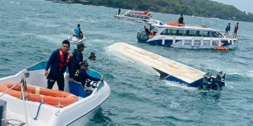 Uomini su barche soccorrono una barca capovolta in mare aperto