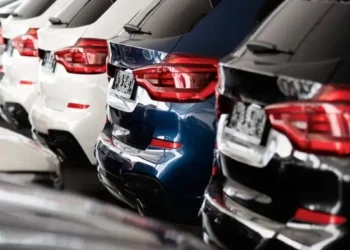 Fila di automobili nuove bianche, blu e nere in concessionaria.