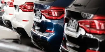 Fila di automobili nuove bianche, blu e nere in concessionaria.