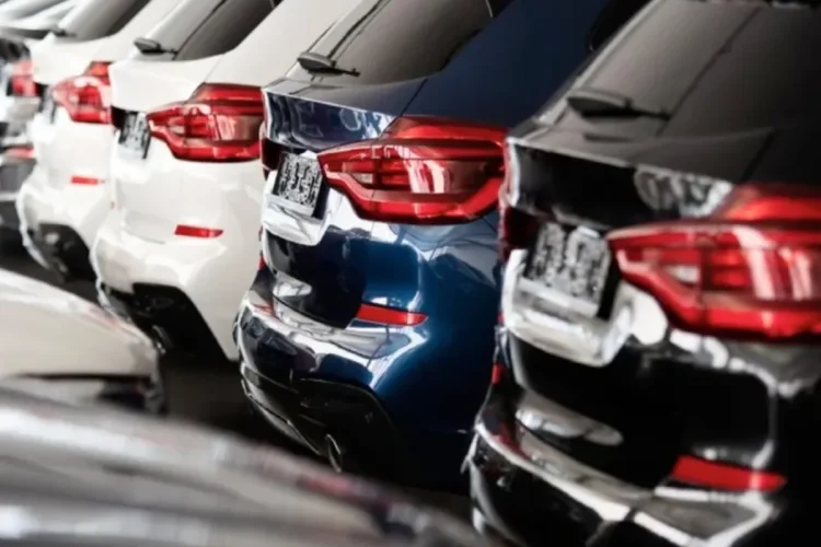 Fila di automobili nuove bianche, blu e nere in concessionaria.