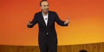 Roberto Benigni gesticola sul palco con un completo scuro