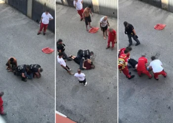 Poliziotti e soccorritori assistono un uomo a terra durante un intervento.