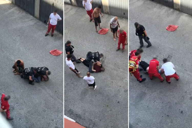 Poliziotti e soccorritori assistono un uomo a terra durante un intervento.