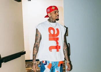 Chris Brown cammina con cappellino rosso e jeans patchwork